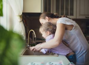 Child washing hands with caregiver.