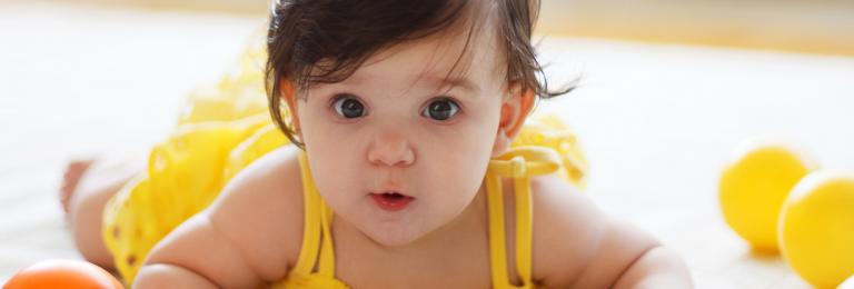 Infant girl crawling after balls