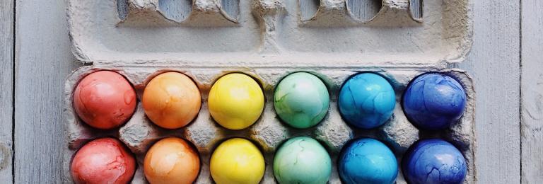 Coloured eggs in an egg carton.